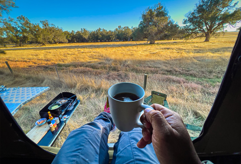 POV menikmati kopi dengan pemandangan pagi di sebuah ladang gandum.