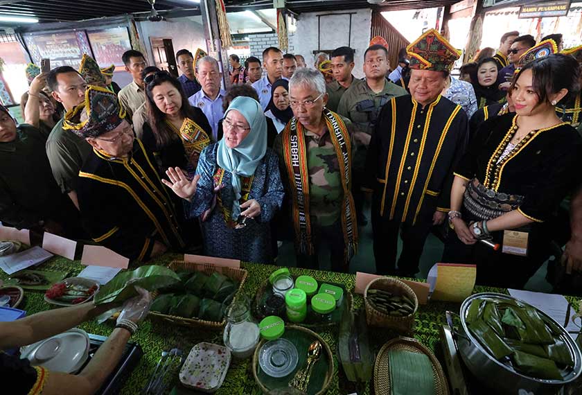 Baginda berdua  berkenan mencuba pelbagai jenis makanan tradisional ketika melawat Perkampungan Budaya, Kadazan Dusun Cultural Association Sabah (KDCA) Penampang hari ini. - Foto Bernama