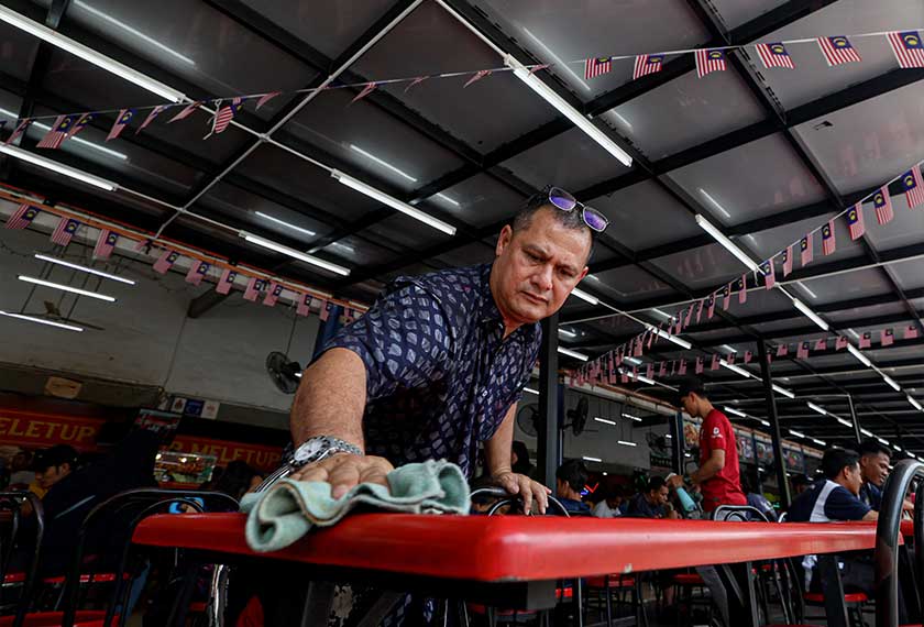 Pemilik gerai Sup Meletup, Zolkhoari Abdul Aziz di Bandar Sri Permaisuri membersihkan tempat duduk pelanggan ketika tinjauan baru-baru ini. - Foto Bernama