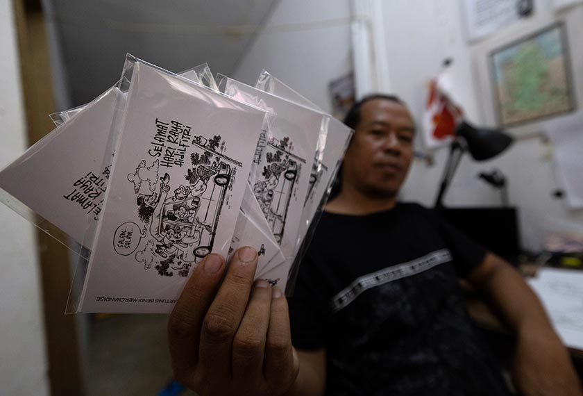 Bendi menunjukan hasil lukisan karya kartun untuk sampul duit raya yang dihasilkan beliau. - Gambar/ Bernama
