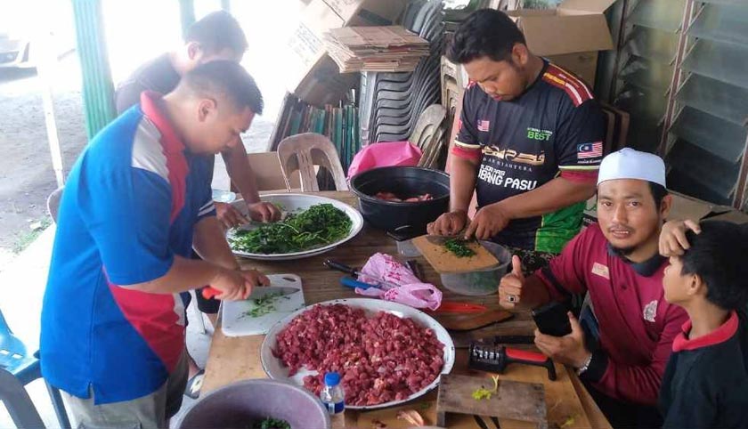 Anak muda bergotong-royong menyiapkan bahan utama memasak bubur lambuk.