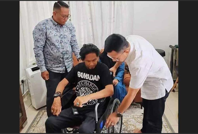 Borhan (kanan) ketika menyerahkan sumbangan kerusi roda kepada Ali (tengah) di kediaman penyanyi itu di Salak Tinggi.