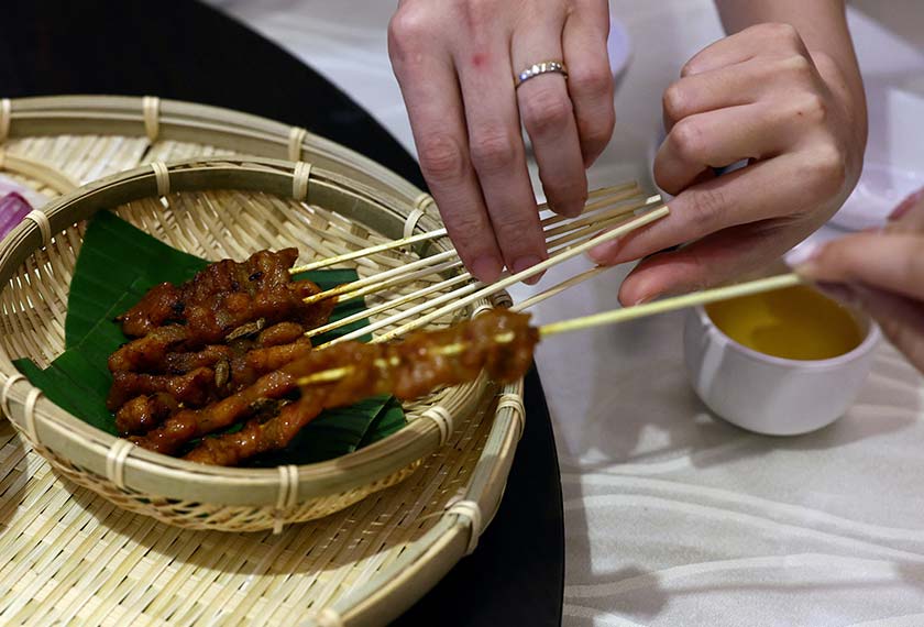 Food testers try a plate of satay sprinkled with house crickets at the House of Seafood restaurant in Singapore. - REUTERS