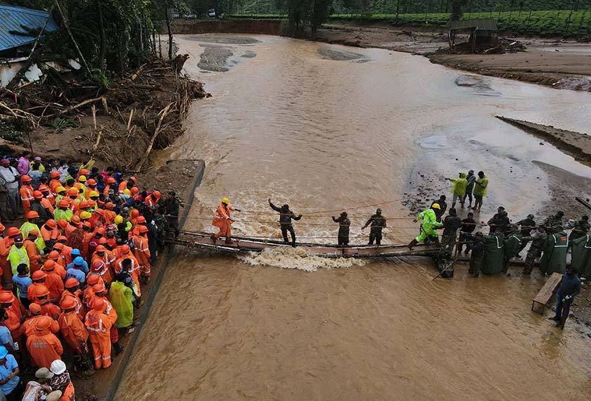 A drone view shows members of rescue teams crossing a temporary bridge to reach to a landslide site after multiple landslides in the hills in Wayanad district, in the southern state of Kerala, India, July 31, 2024. - REUTERS