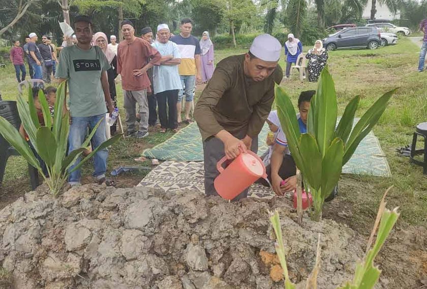 Mohd Azril menyiram air ke kubur anaknya di Tanah Perkuburan Islam Kampung Teluk Piai di sini pada Rabu. - Foto Sinar Harian