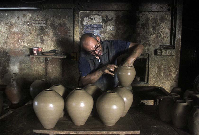 A person works in a pottery workshop as Palestinians respond to an increase in the demand for clay pots used to cool water due to power cuts and hot weather, according to workers. - REUTERS