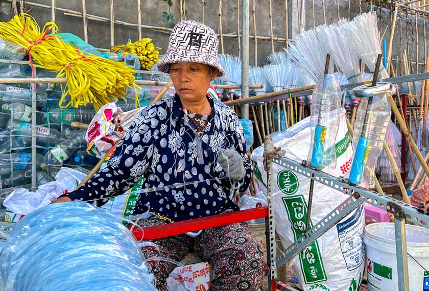 A woman works on a plastic broomstick at a warehouse in Phnom Penh, Cambodia. - REUTERS