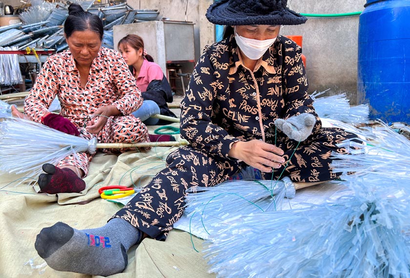 Women work on plastic broomsticks at a warehouse in Phnom Penh, Cambodia. - REUTERS