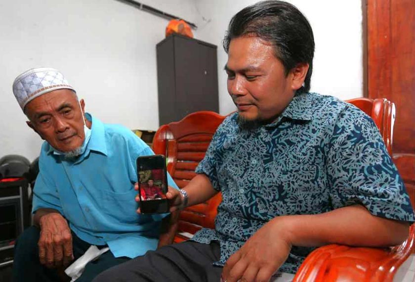 Mohd Asna (kanan) menunjukkan gambar Allahyarham sambil diperhatikan Samad. - Foto Sinar Harian
