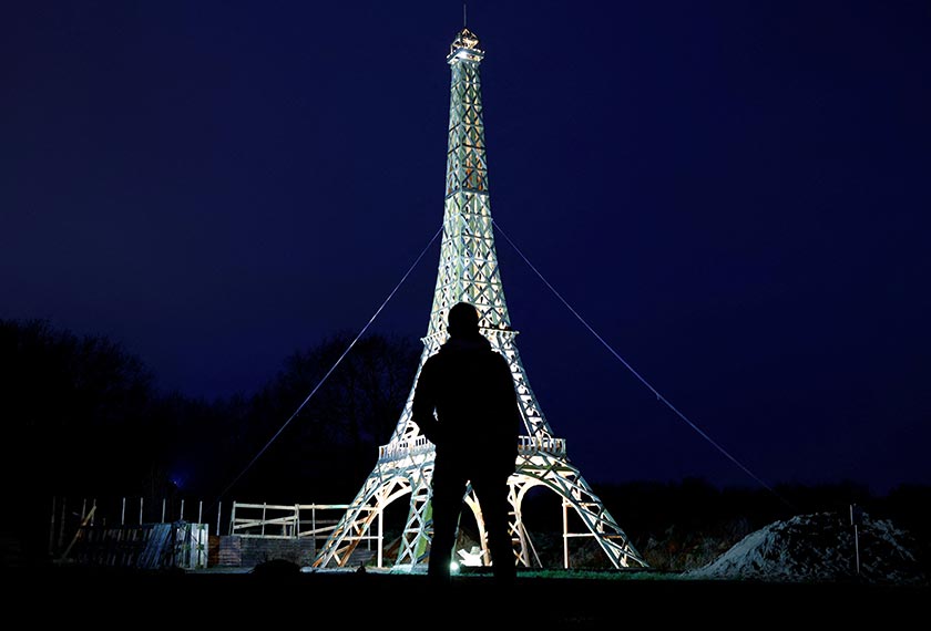 A man stands in front of a 16-meter replica of the Eiffel Tower from recycled wood built by French carpenter Frederic Malmezac and Sylvain Bouchard,  France. - REUTERS 