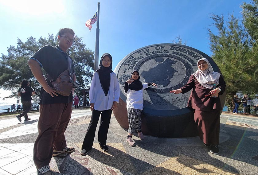 Tiga beradik (dari kiri) Ainur Madhiah Fadzli, 19, Atif Isfahan, 17, dan Amni Umaira, 10, yang berkunjung ke Tanjung Simpang Mengayau tertarik melihat peta kedudukan Tanjung Simpang Mengayau. - Foto BERNAMA
