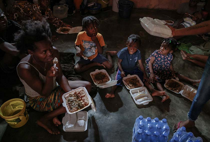 People displaced by gang war violence eat food distributed by a community action center, with the assistance of the United Nations World Food Programme, inside a classroom at Jeunes Filles high school, which was turned into a shelter where people live in poor conditions, in Port-au-Prince, Haiti. - REUTERS