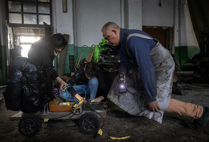 Dmytro Mamonov, his wife Oksana and their son Yelisei, 14, look at a test vehicle in their workshop where they produce remote-controlled medical evacuation vehicles for the military. - REUTERS