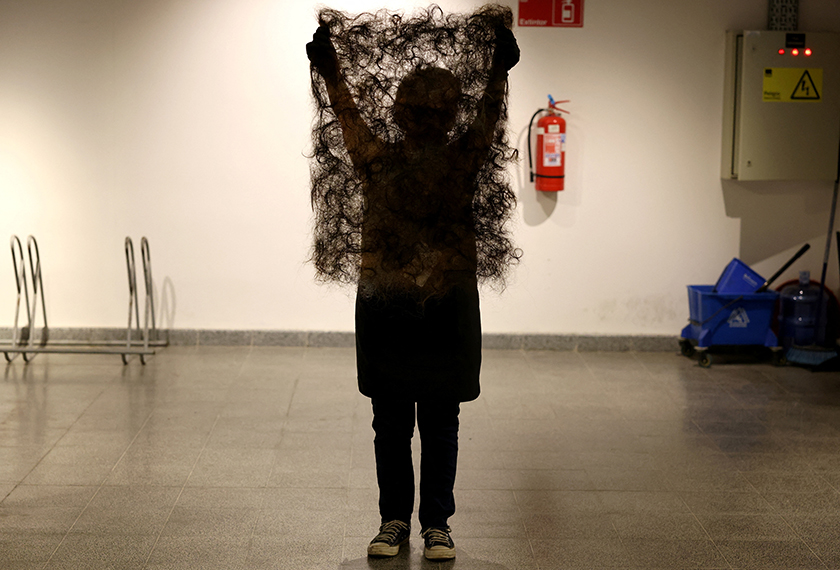 A member of Matter of Trust Chile holds up a mat made from human hair that they use to make 'Petropelo', a system that utilizes hair's natural absorbent qualities to clean waterways of oils, heavy metals, and even bacteria, in Santiago, Chile. - REUTERS