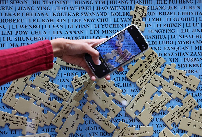A visitor takes a picture of the well-wishes placed on the names of crew members and passengers of the missing Malaysia Airlines flight MH370, displayed during a remembrance event marking the 10th anniversary of its disappearance, in Subang Jaya, Malaysia March 3, 2024. - REUTERS