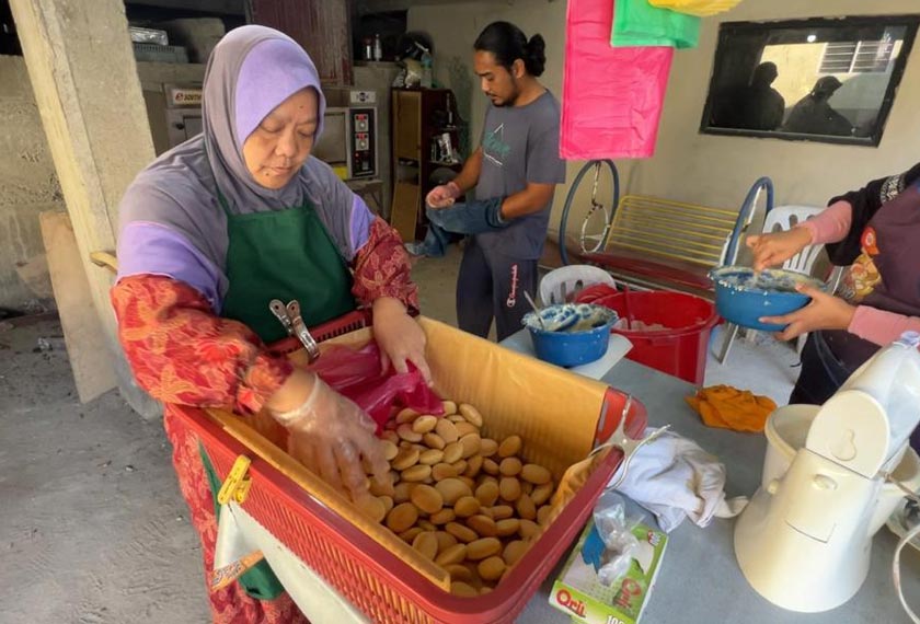 Maimun Embong (kiri) bersama anak dan menantu sibuk menyiapkan tempahan nekbat.
