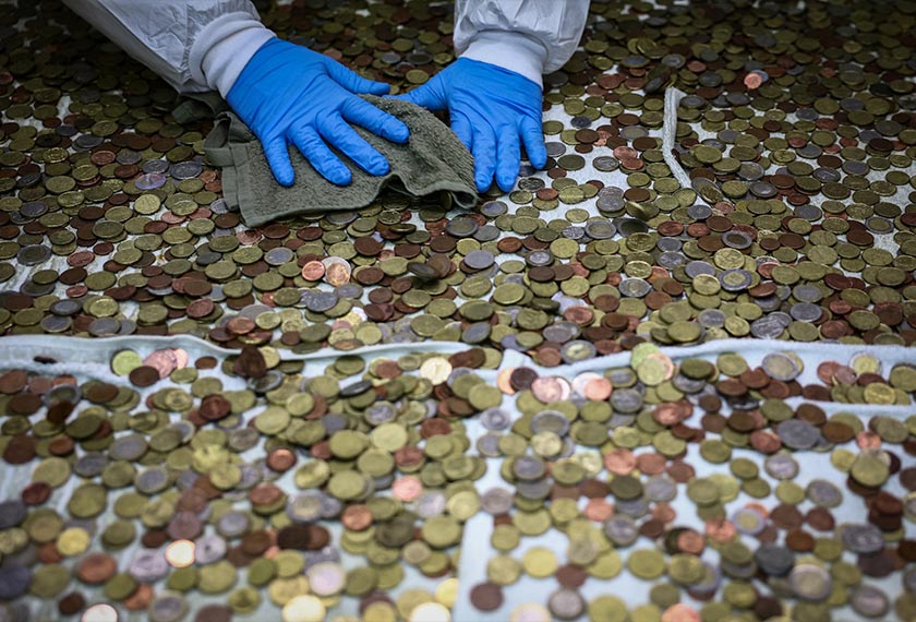 Catholic charity Caritas employee Fabrizio Marchioni, 52, dries coins collected at the Trevi Fountain, at the Caritas office in Rome, Italy. - REUTERS