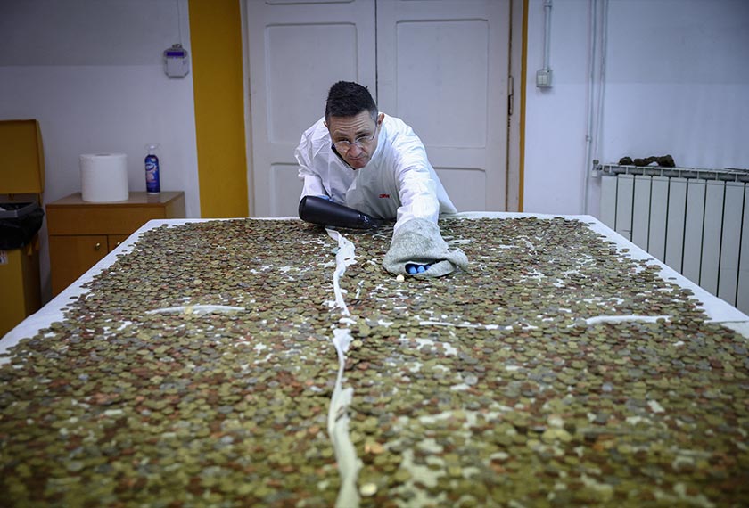 Catholic charity Caritas employee Fabrizio Marchioni, 52, uses a hairdryer to dry coins collected at the Trevi Fountain, at the Caritas office in Rome, Italy. - REUTERS