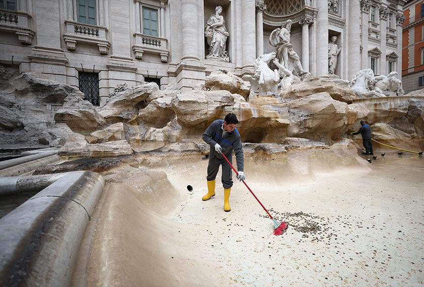 ACEA utility worker Alexio Cola uses a broom to gather coins to be collected in the emptied Trevi Fountain in Rome, Italy. - REUTERS