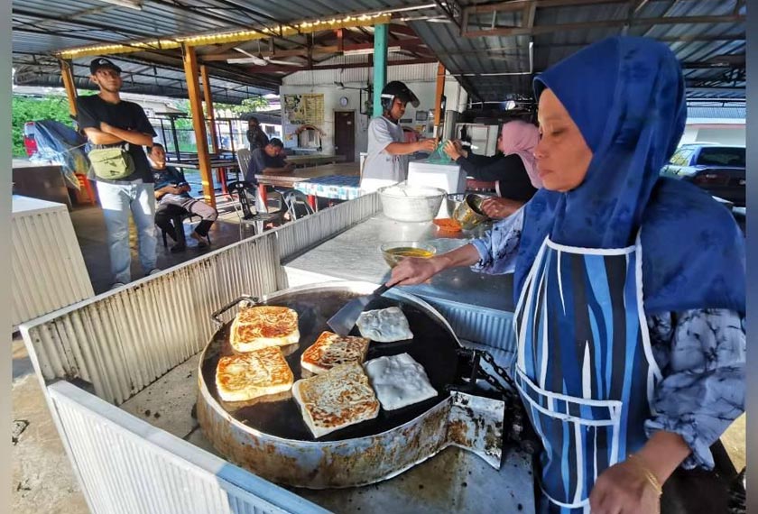 Jamilah menyediakan martabak yang dipesan pelanggan di gerainya yang beroperasi di Chabang Tiga, Kuala Terengganu.