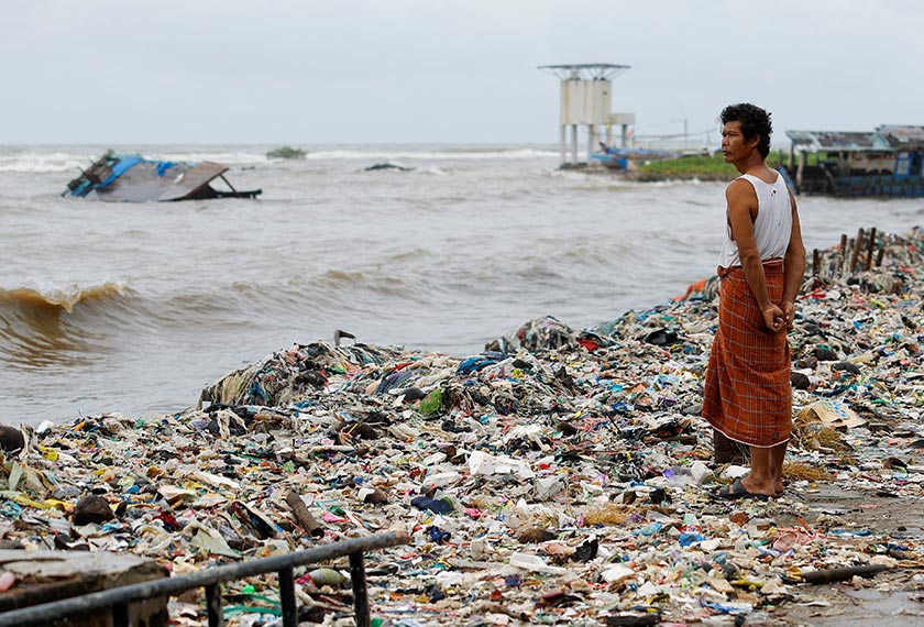 A man stands near trash, mostly plastics and domestic waste, on a beach in Teluk fishing village, as high tides brought by erratic weather sweeps trash to the shore, in Pandeglang regency, Banten province, Indonesia. - REUTERS