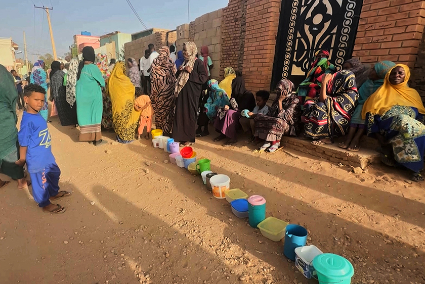 Residents wait to collect food in containers from a soup kitchen in Omdurman. - REUTERS