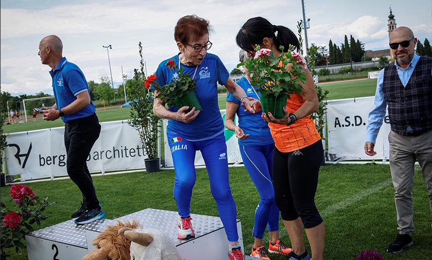 Elena Righi helps Italian master runner Emma Maria Mazzenga, 90, step down the podium after Mazzenga won the women's 100m W90 category race, in San Biagio di Callalta, Treviso, Italy. - REUTERS