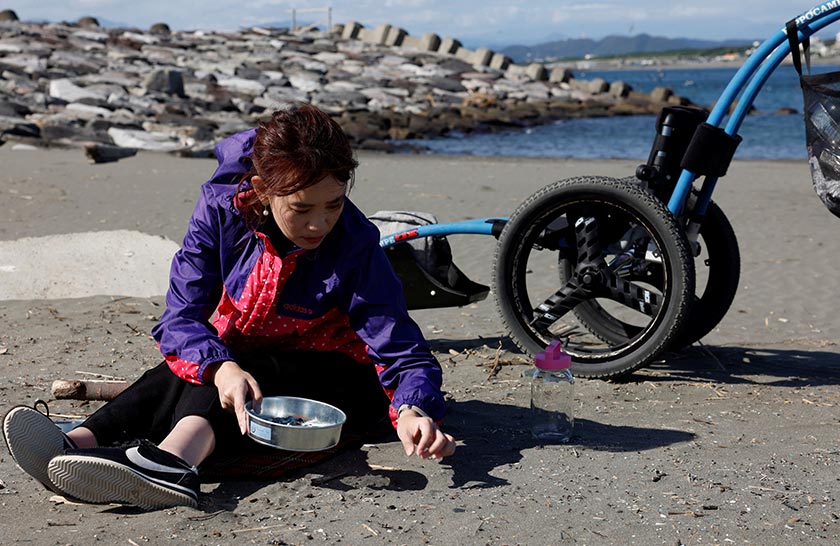 Japanese manicurist Naomi Arimoto collects plastic waste from the sand at a beach in Chigasaki, Kanagawa Prefecture, Japan. - REUTERS/Manami Yamada