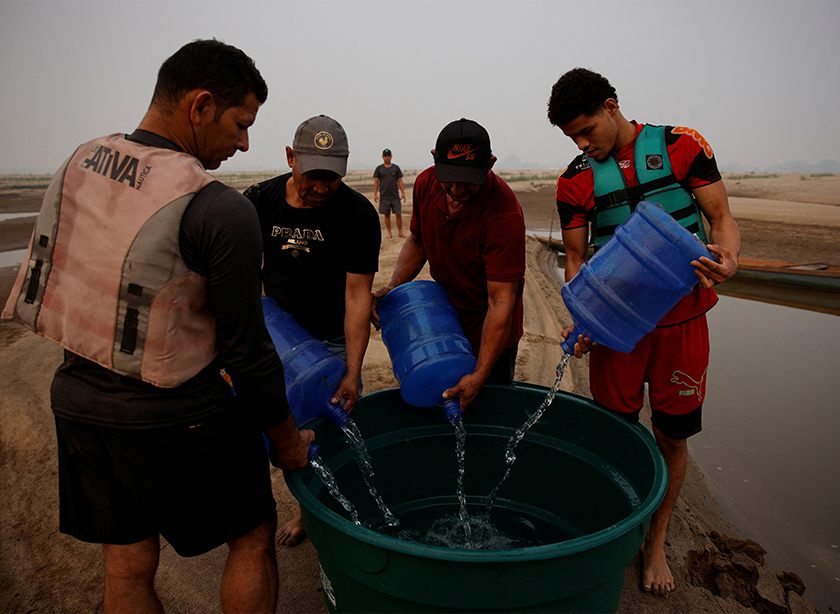 River dwellers fill a tank of water on the sandbanks of the Madeira river to bring to the isolated region of Paraizinho community, during the worst drought of the river in history, Humaita, Amazonas state, Brazil September 8, 2024. - REUTERS