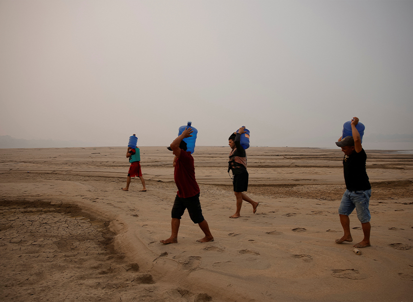 River dwellers carry water gallons on the sandbanks of the Madeira river to bring to the isolated region of Paraizinho community, during the worst drought of the river in history, Humaita, Amazonas state, Brazil September 8, 2024. - REUTERS