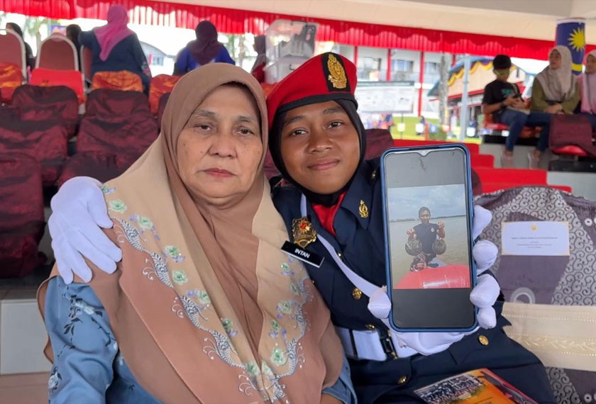 Intan Norhafiza menunjukkan gambar arwah abangnya sambil memeluk ibunya, - Foto Astro AWANI