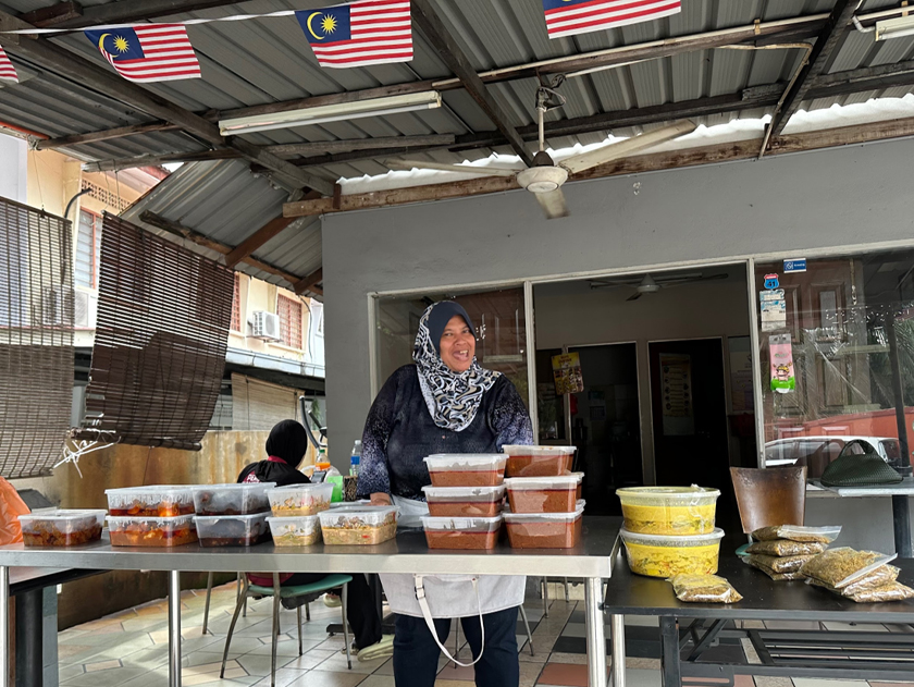 Mak Ja, 55, dan anak-anak buahnya bergurau senda sambil menyediakan pesanan bawa pulang hidangan Nasi Ambeng untuk sambutan Hari Raya Haji. 