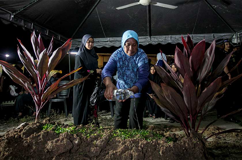 Suriati menyiram air ke pusara anaknya, Damarrulan, di Tanah Perkuburan Islam Kampung Kepayang, Ipoh, 14 Mei 2025. --fotoBERNAMA