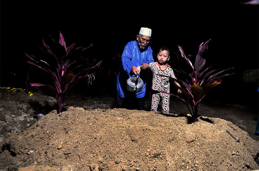 Samiun Sarif, 73, (kiri) bersama cucunya Muhammad Rizqi Nazhan Mohd Roslan, 9, menyiram air mawar di pusara Allahyarham Sarjan Mohd Roslan Abd Rahim, 46, di Tanah Perkuburan Islam Taman Meru, Ipoh. --fotoBERNAMA
