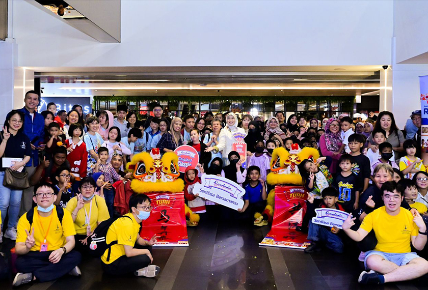 Ena bersama peserta daripada tujuh organisasi kebajikan bergambar kenangan diiringi kumpulan tarian singa, melambangkan kemeriahan dan semangat kebersamaan dalam program Hari Ceria Bersama Gardenia sempena Tahun Baharu Cina 2026. - Gambar Gardenia