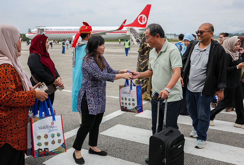 Pengerusi Jawatankuasa Perpaduan, Pelancongan dan Kebudayaan Pahang Leong Yu Man (tiga, kiri) menyambut ketibaan para penumpang dan pelancong yang menaiki pesawat MAS di Lapangan Terbang Sultan Haji Ahmad Shah, Kuantan. --fotoBERNAMA