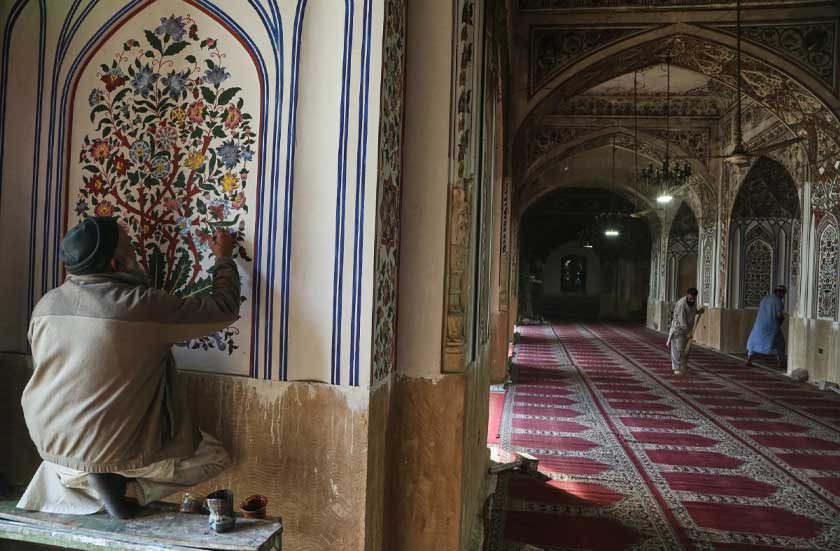 A painter gives finish touches to an artwork as workers clean an area of the historic Mahabat Khan mosque in preparation for the upcoming Muslim fasting month of Ramadan, in Peshawar, Pakistan, Monday, Feb. 16, 2026. (AP Photo/Muhammad Sajjad)