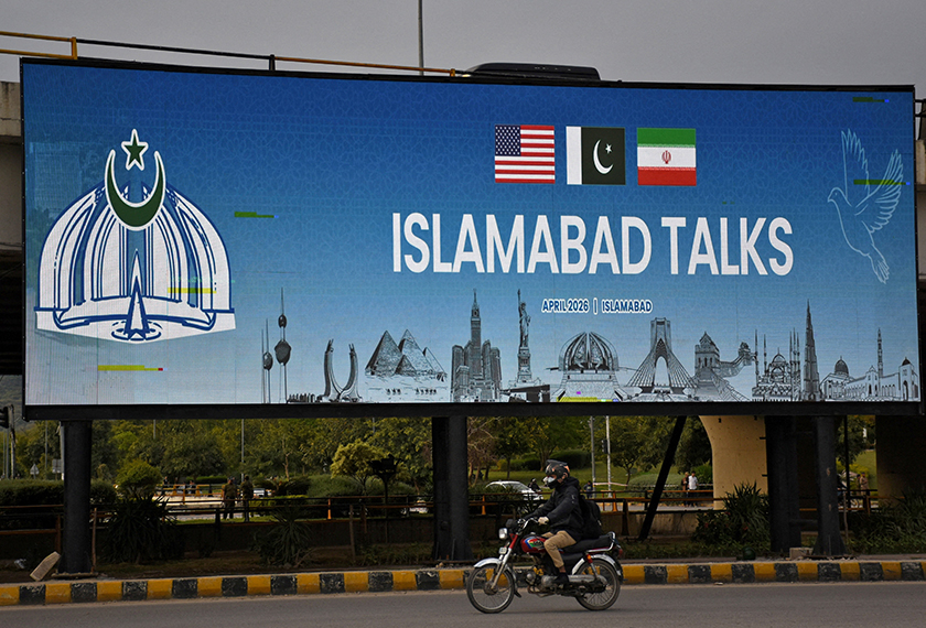 A man rides his motorbike past a billboard installed alongside a road as Pakistan prepares to host the U.S. and Iran for peace talks, in Islamabad, Pakistan, April 10, 2026. REUTERS/Waseem Khan 